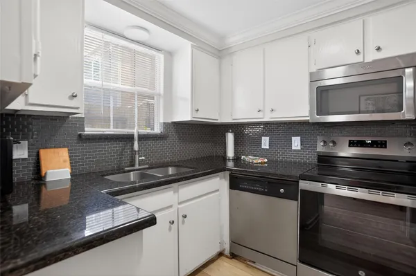 a kitchen with granite countertop white cabinets and black appliances