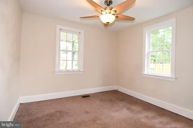 an empty room with a window and a fan