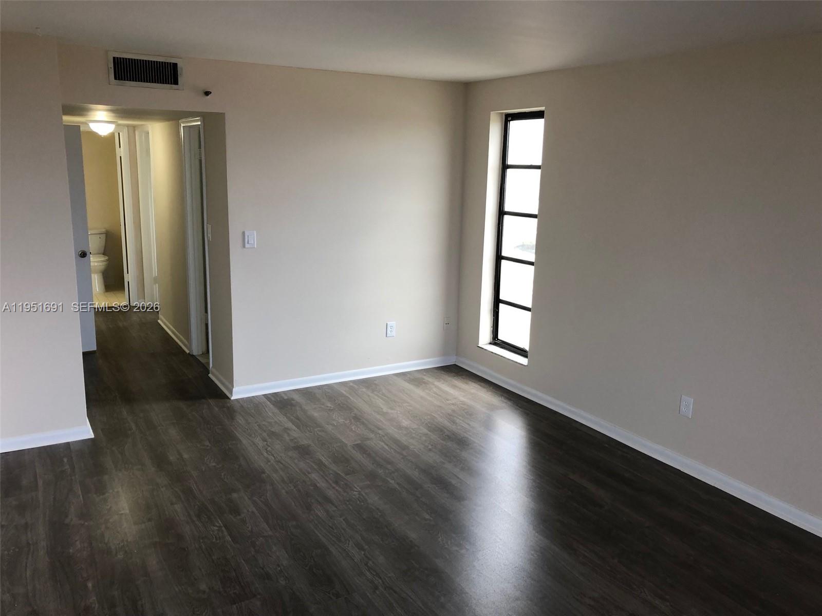 20840 San Simeon Way, Unit 702 Miami, FL 33179 - Photo 16 of 34 an empty room with wooden floor and windows