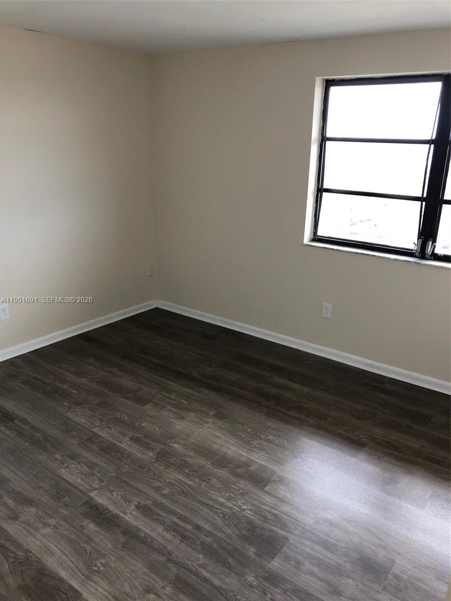 20840 San Simeon Way, Unit 702 Miami, FL 33179 - Photo 24 of 34 a view of an empty room with wooden floor and a window