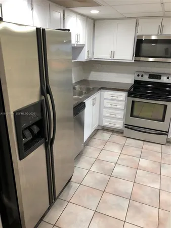 a kitchen with granite countertop a refrigerator and a sink