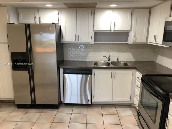 a kitchen with granite countertop white cabinets stainless steel appliances and a sink
