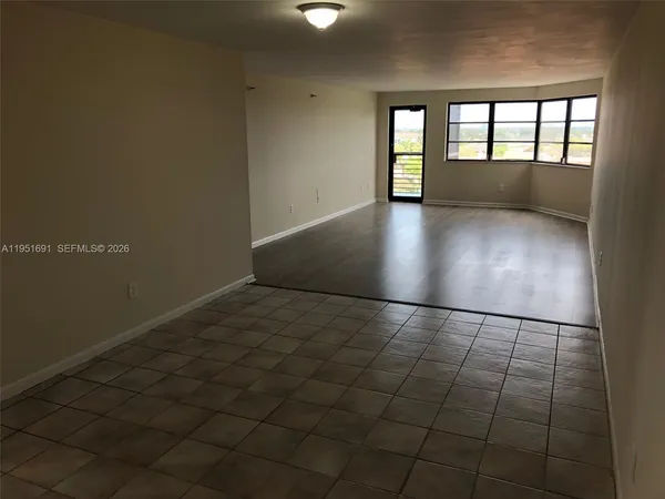 an empty room with wooden floor kitchen and windows