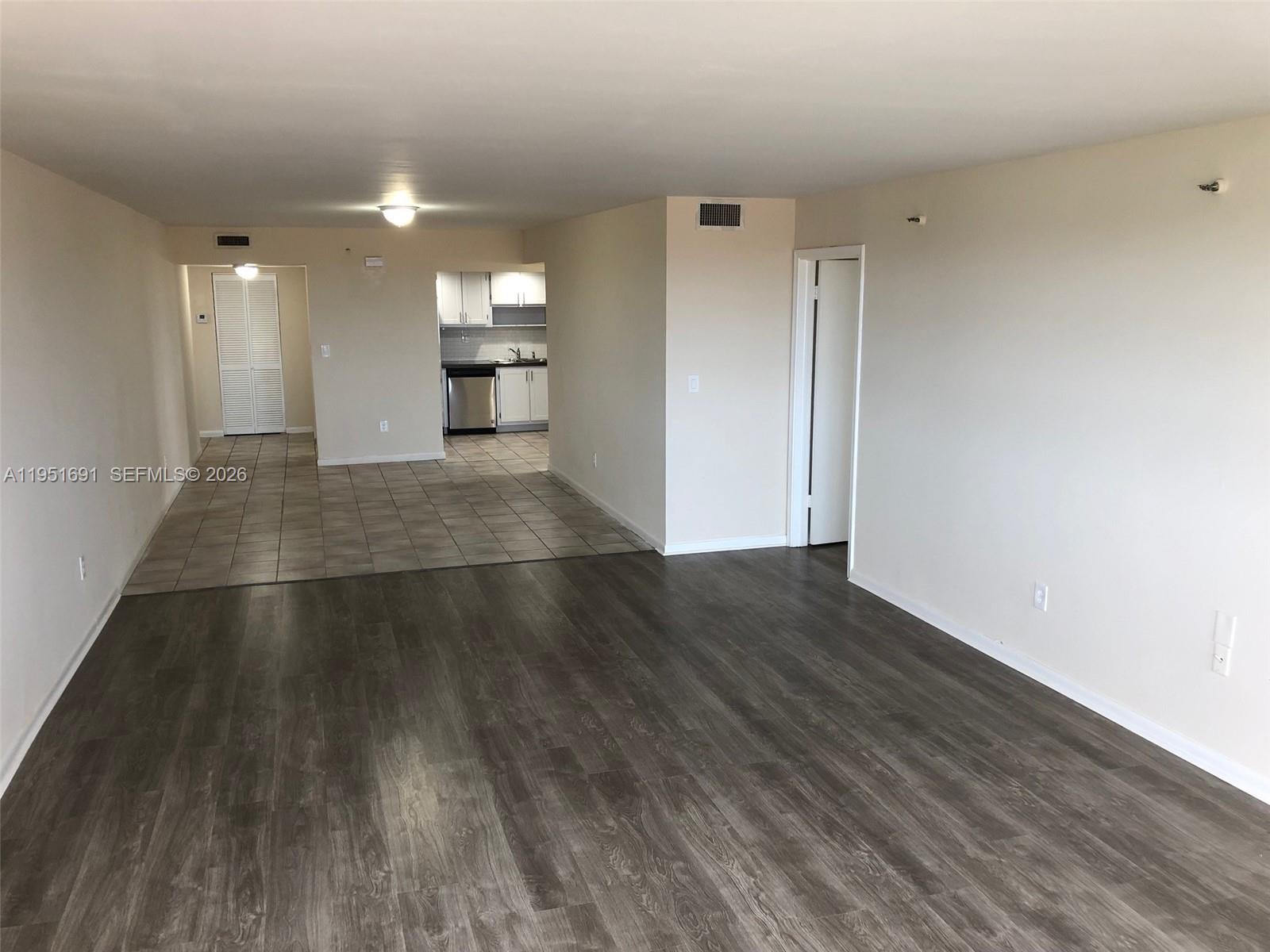 20840 San Simeon Way, Unit 702 Miami, FL 33179 - Photo 10 of 34 an empty room with wooden floor kitchen and windows