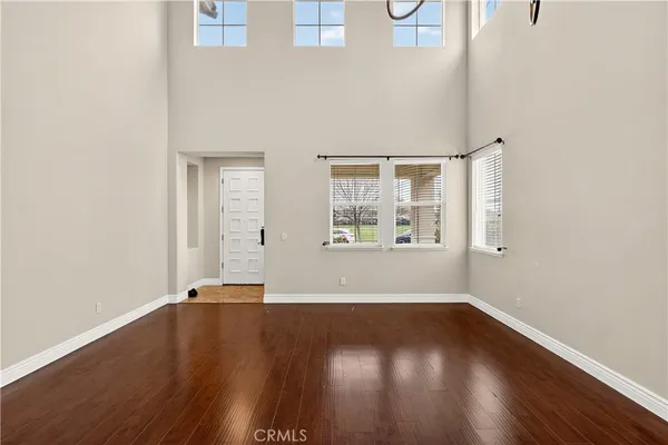 a view of an empty room with window and wooden floor