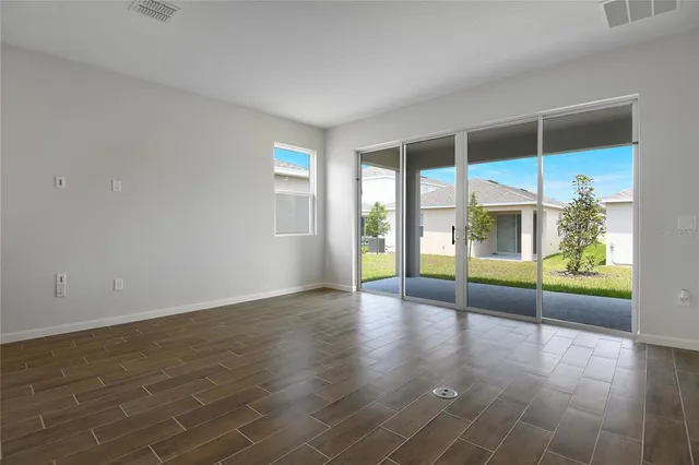 an empty room with sliding glass door and wooden floor