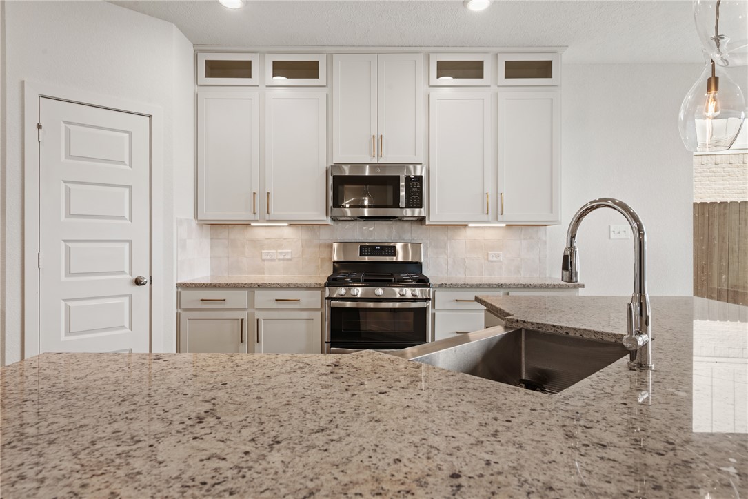5626 Hayduke Ln. Bryan, TX 77802 - Photo 11 of 49 a kitchen with stainless steel appliances granite countertop a stove a sink and a microwave