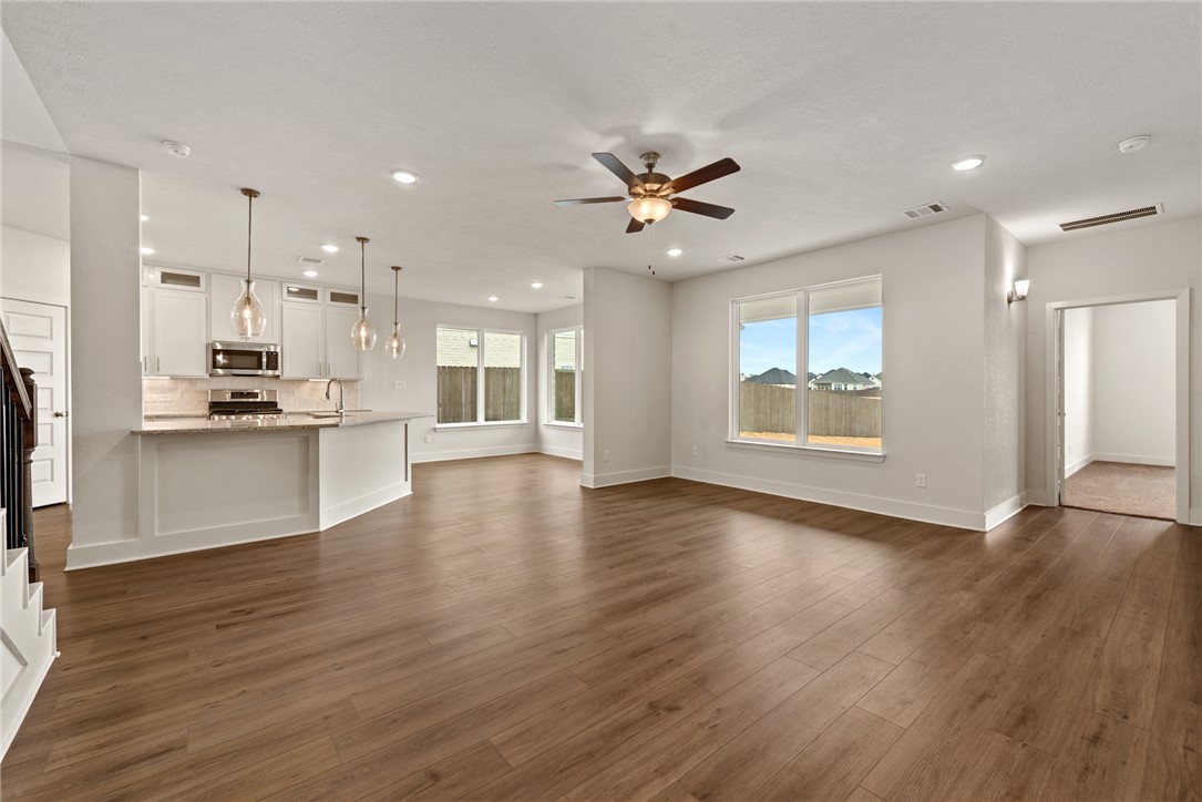 5626 Hayduke Ln. Bryan, TX 77802 - Photo 19 of 49 a view of an empty room with wooden floor and a kitchen