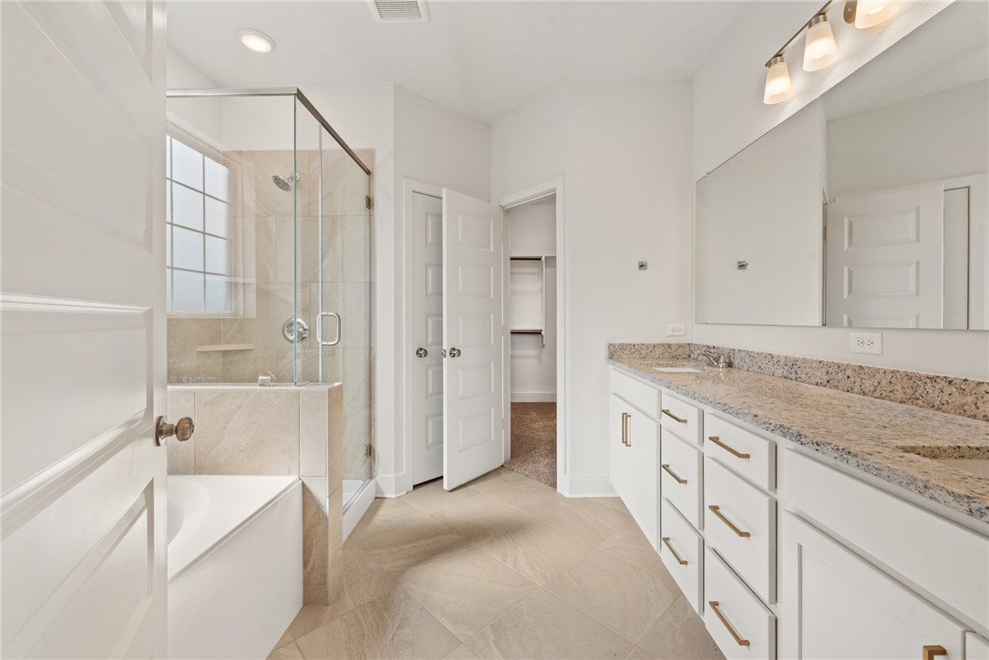 5626 Hayduke Ln. Bryan, TX 77802 - Photo 25 of 49 a spacious bathroom with a granite countertop sink a mirror a shower and a bathtub