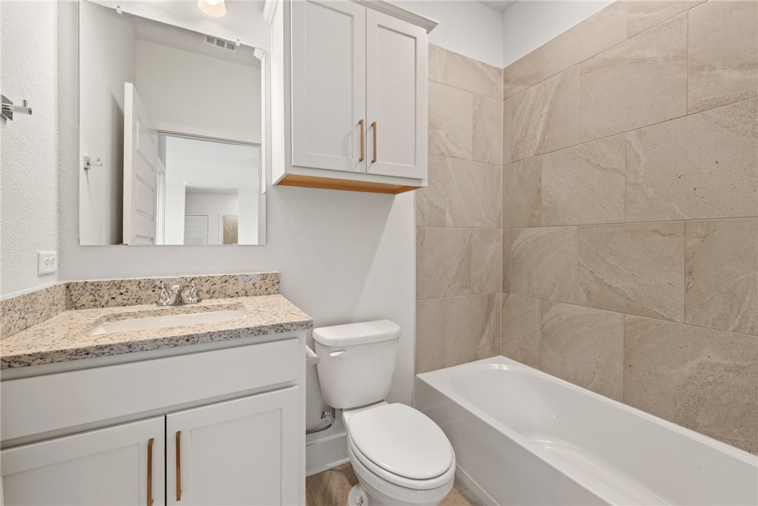 5626 Hayduke Ln. Bryan, TX 77802 - Photo 37 of 49 a bathroom with a granite countertop toilet sink and mirror