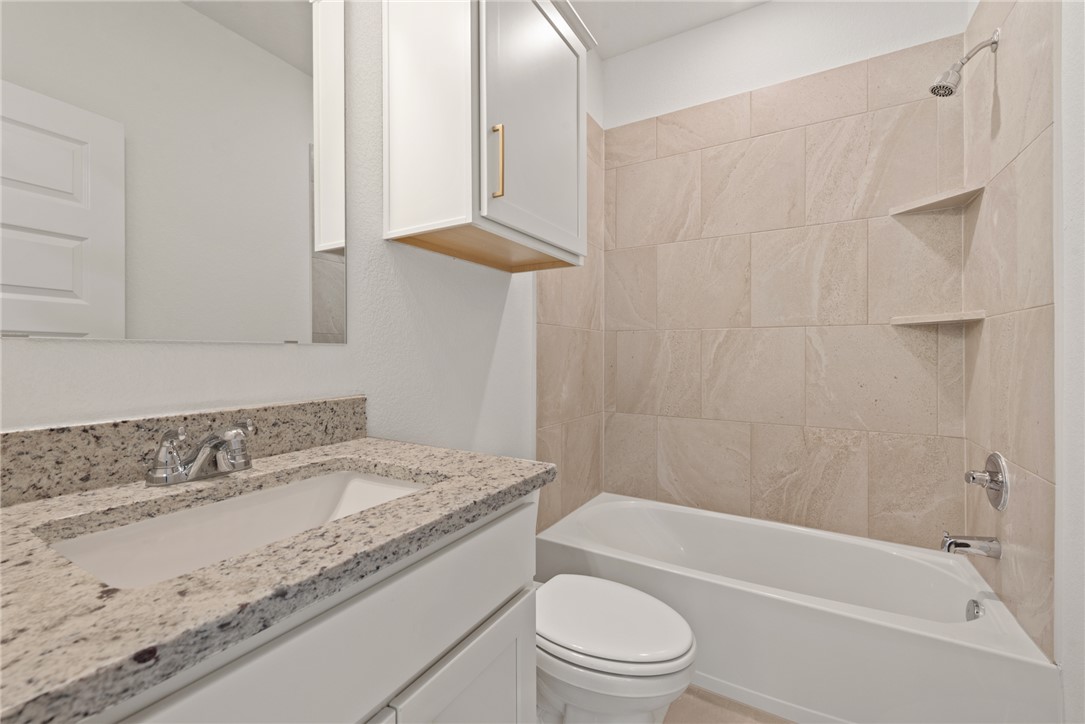 5626 Hayduke Ln. Bryan, TX 77802 - Photo 40 of 49 a bathroom with a granite countertop sink a toilet and bathtub