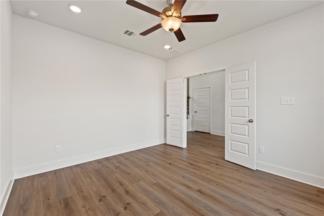 5626 Hayduke Ln. Bryan, TX 77802 - Photo 7 of 49 an empty room with wooden floor closet ceiling fan and windows