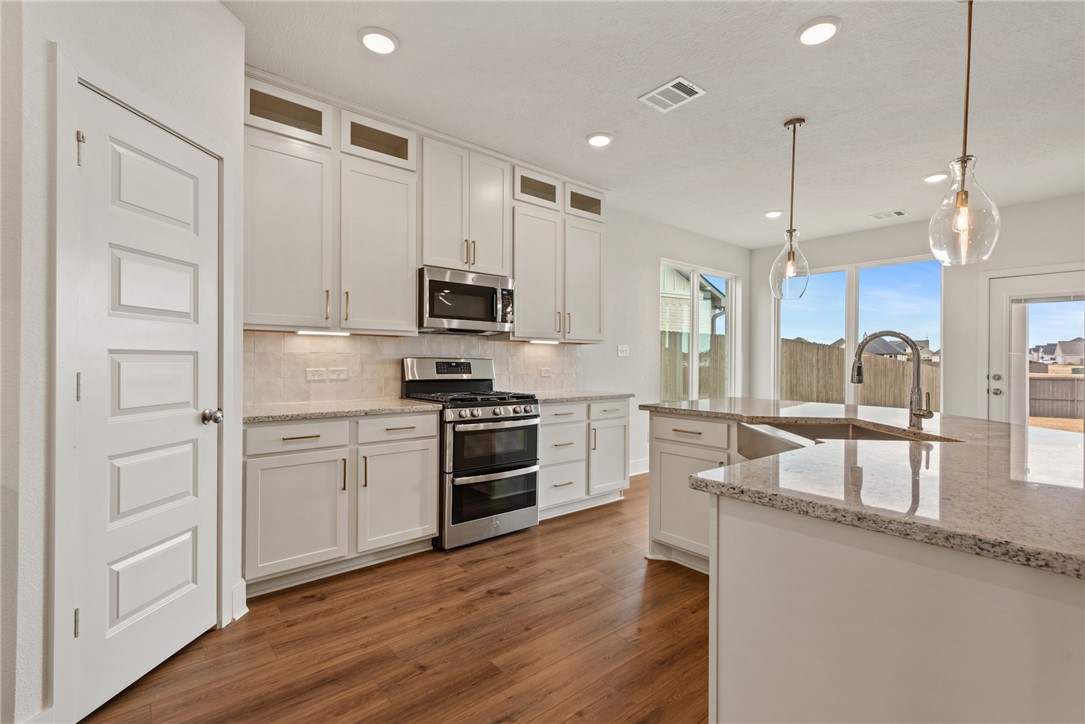 5626 Hayduke Ln. Bryan, TX 77802 - Photo 8 of 49 a kitchen with stainless steel appliances granite countertop a refrigerator a sink dishwasher a oven with white cabinets and wooden floor