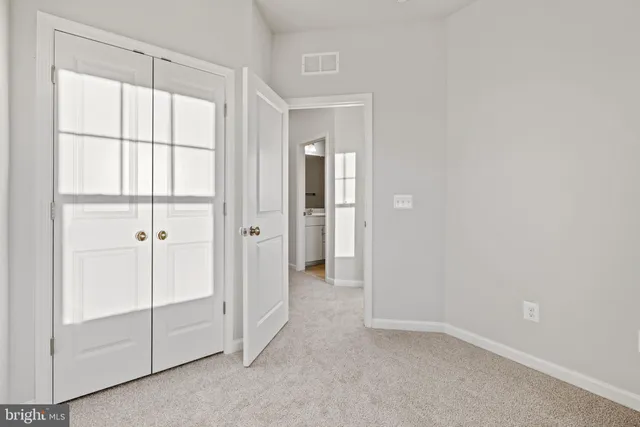 a view of an empty room with closet and a window