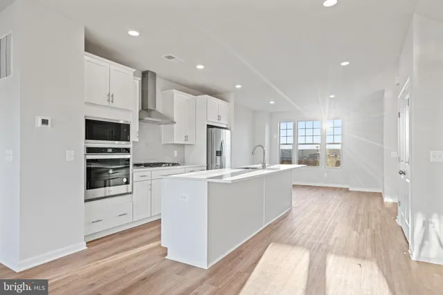 a kitchen with stainless steel appliances a refrigerator a stove a microwave and white cabinets