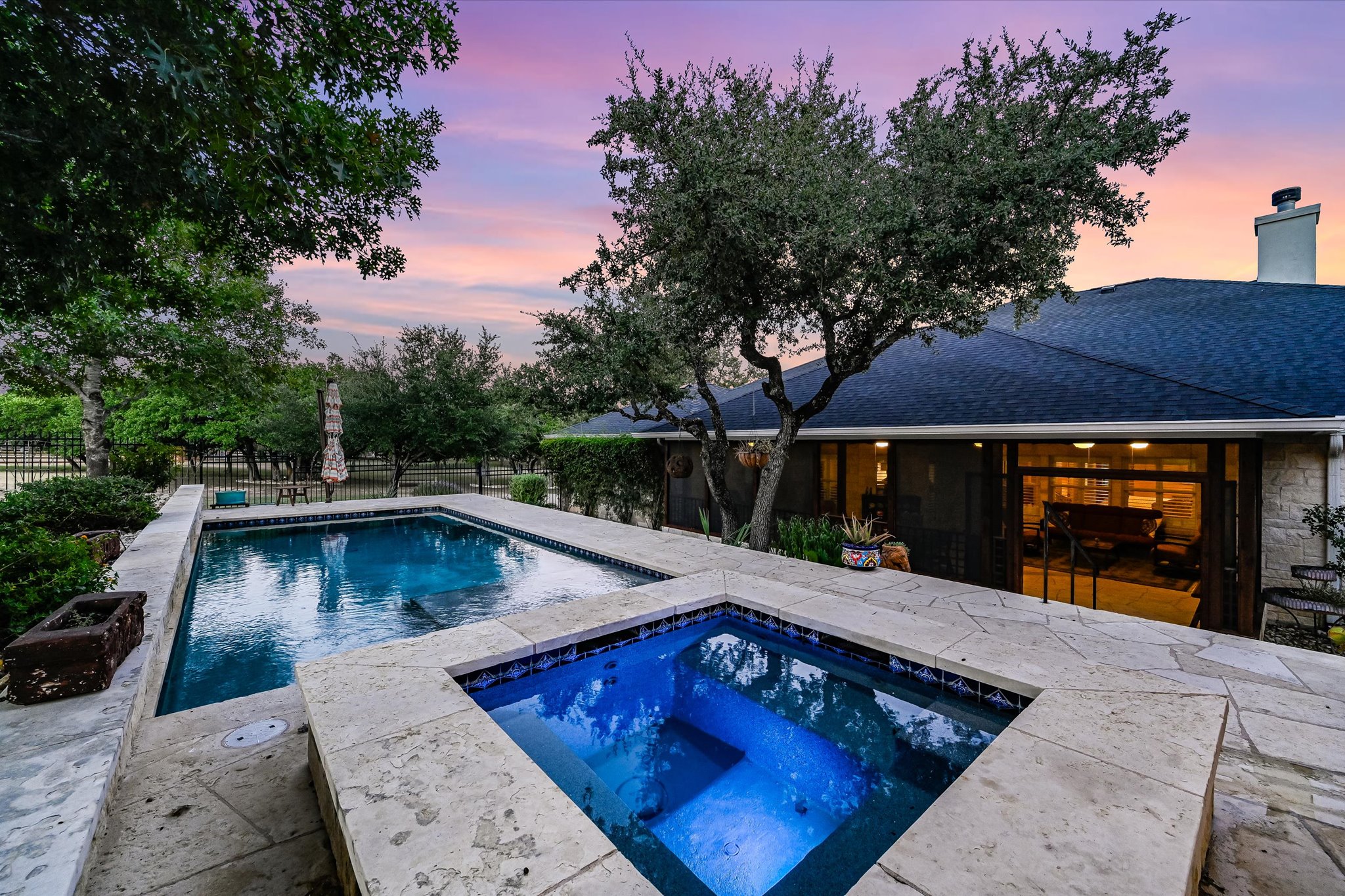 786 Ranchers Club Lane Driftwood, TX 78619 - Photo 3 of 33 Pool at dusk with an in-ground hot tub, a patio, and a fenced backyard