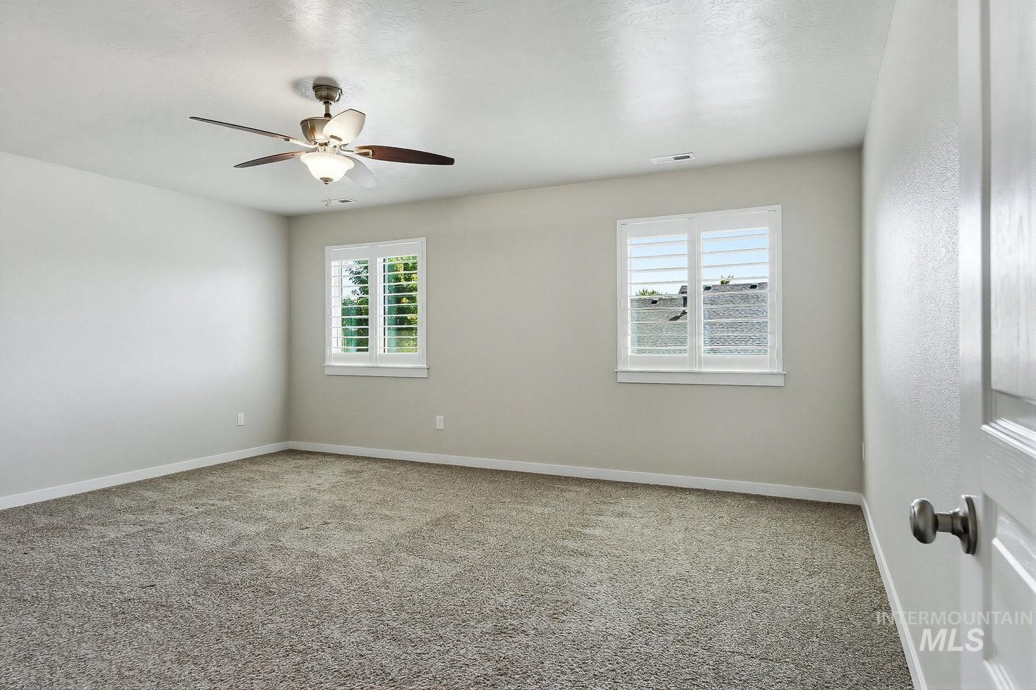 846 North Hidden View Way Star, ID 83669 - Photo 31 of 49 Spacious room featuring neutral-toned carpeting, two windows with plantation shutters, a ceiling fan with integrated lighting, and light-colored walls with white trim