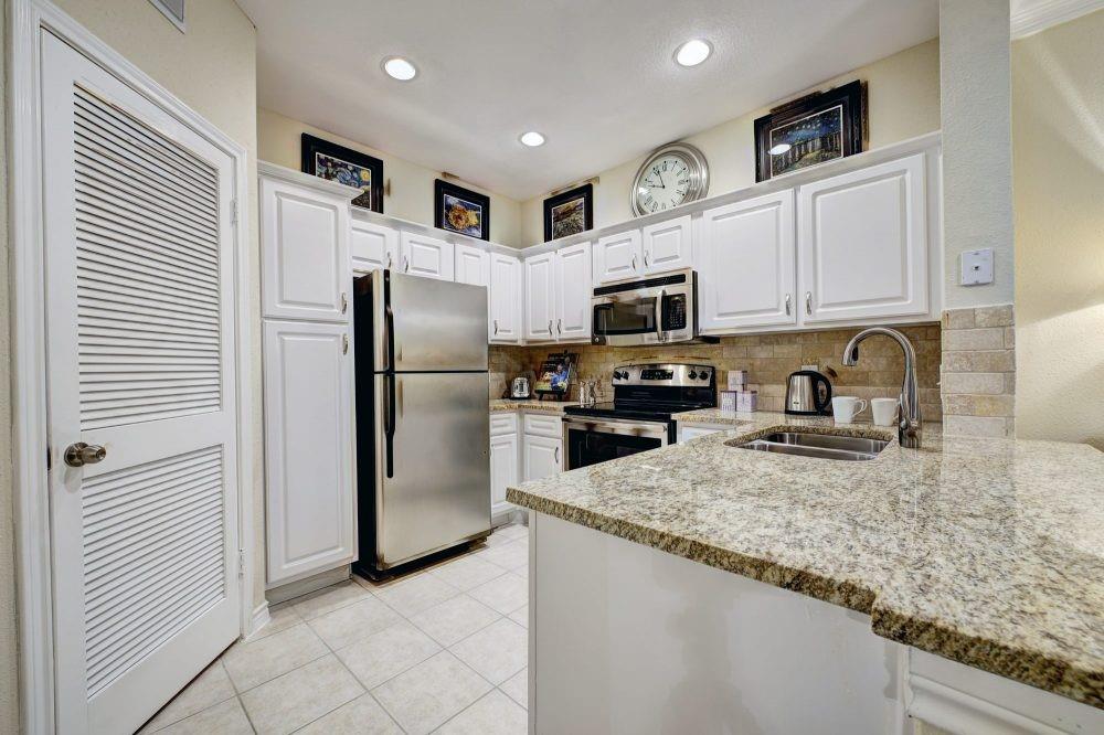 a kitchen with granite countertop a refrigerator a sink a stove a microwave and island
