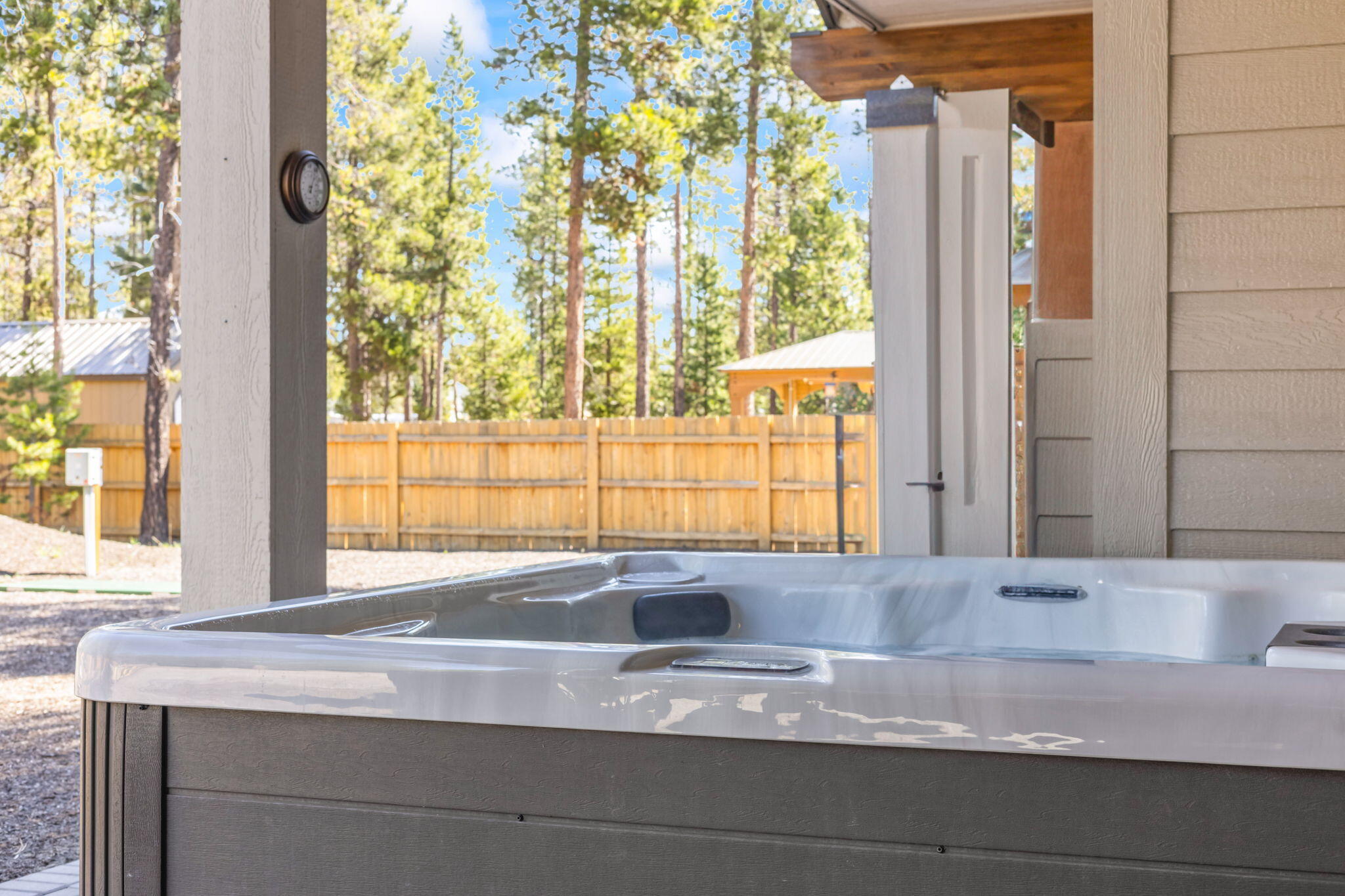 17138 Downey Road Bend, OR 97707 - Photo 37 of 57 Covered patio with 8-person hot tub, fully fenced yard, and serene pine surroundings.