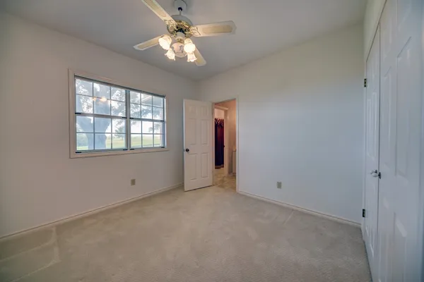 an empty room with chandelier fan and windows