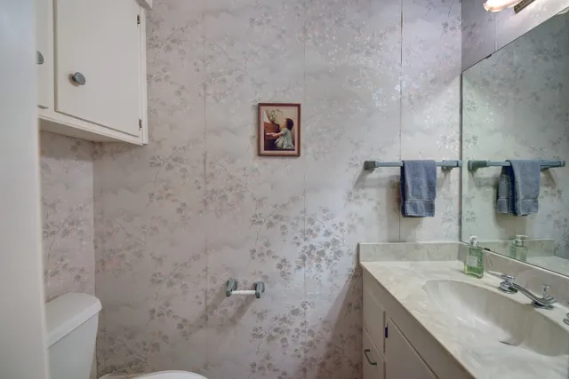 a bathroom with a granite countertop sink toilet and mirror