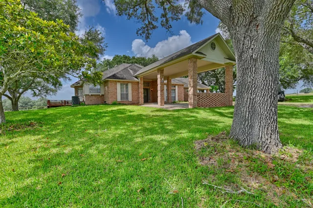 a view of a house with a big yard and large tree