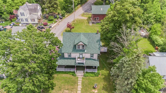 an aerial view of a house with swimming pool a yard and a large tree
