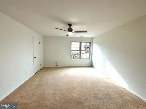 an empty room with a ceiling fan and window