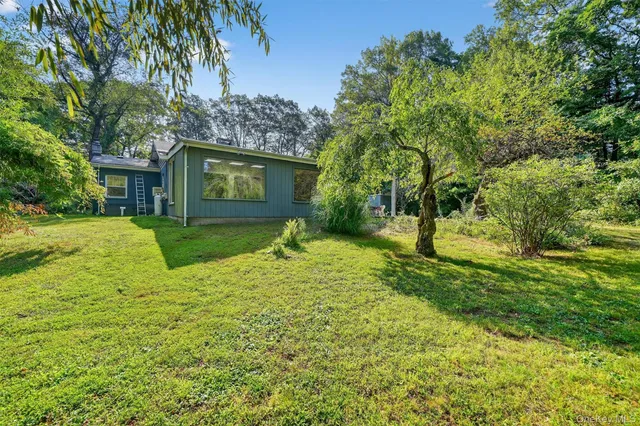 a view of a yard in front of a house with large tree
