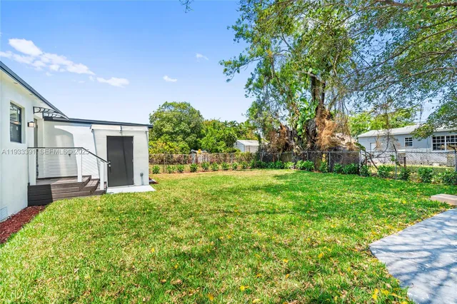 a backyard of a house with plants and large trees