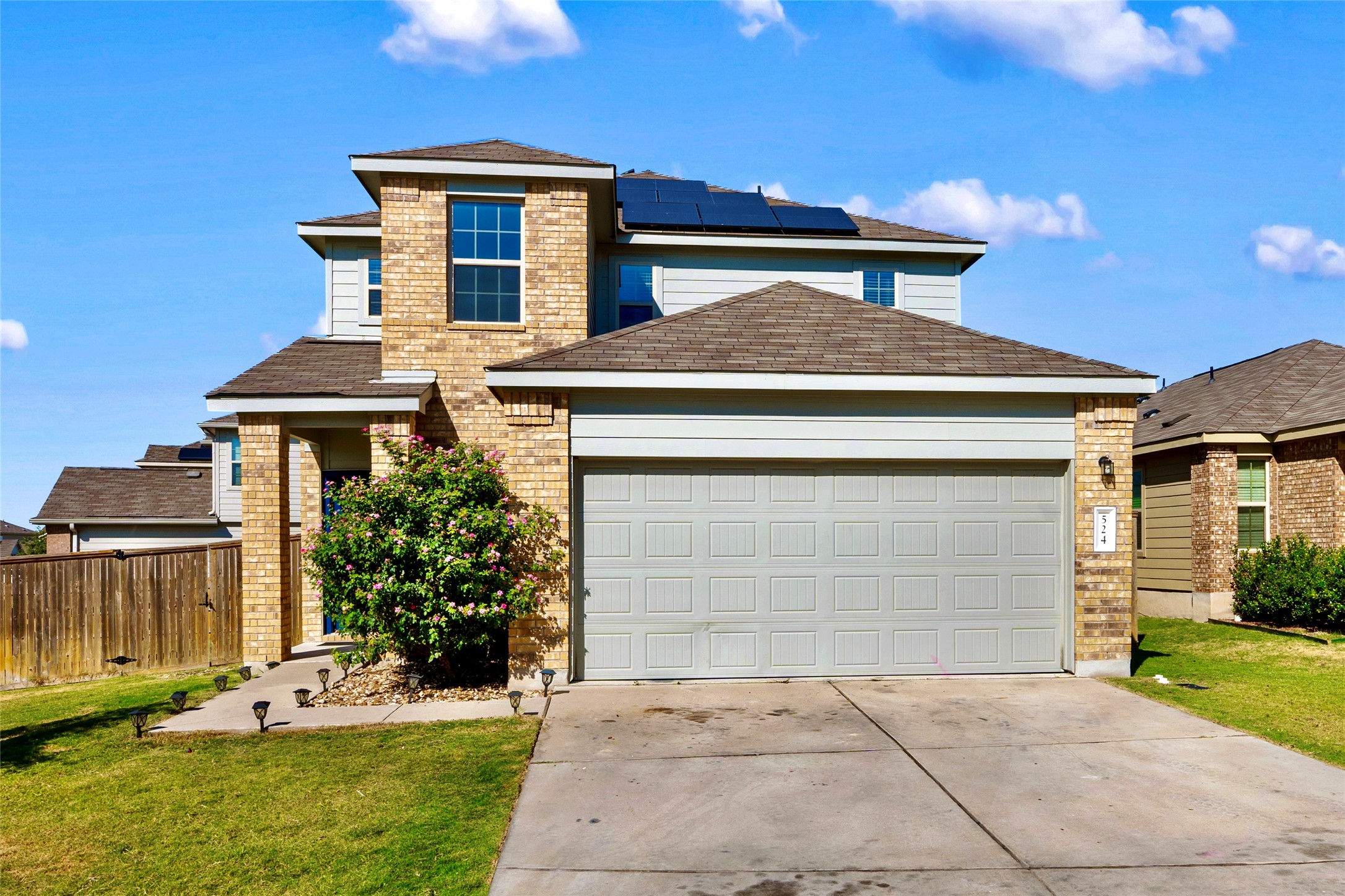 Traditional-style home with roof mounted solar panels, a garage, brick siding, and concrete driveway