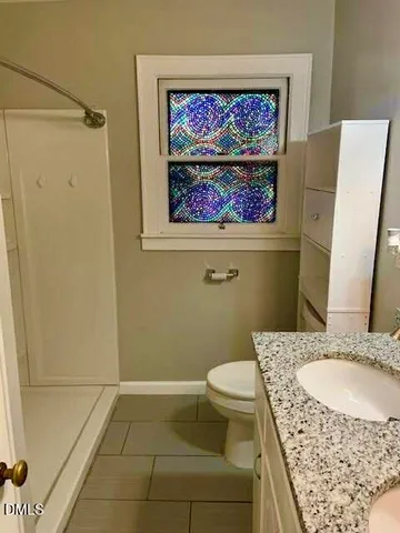 a bathroom with a granite countertop sink mirror vanity and toilet