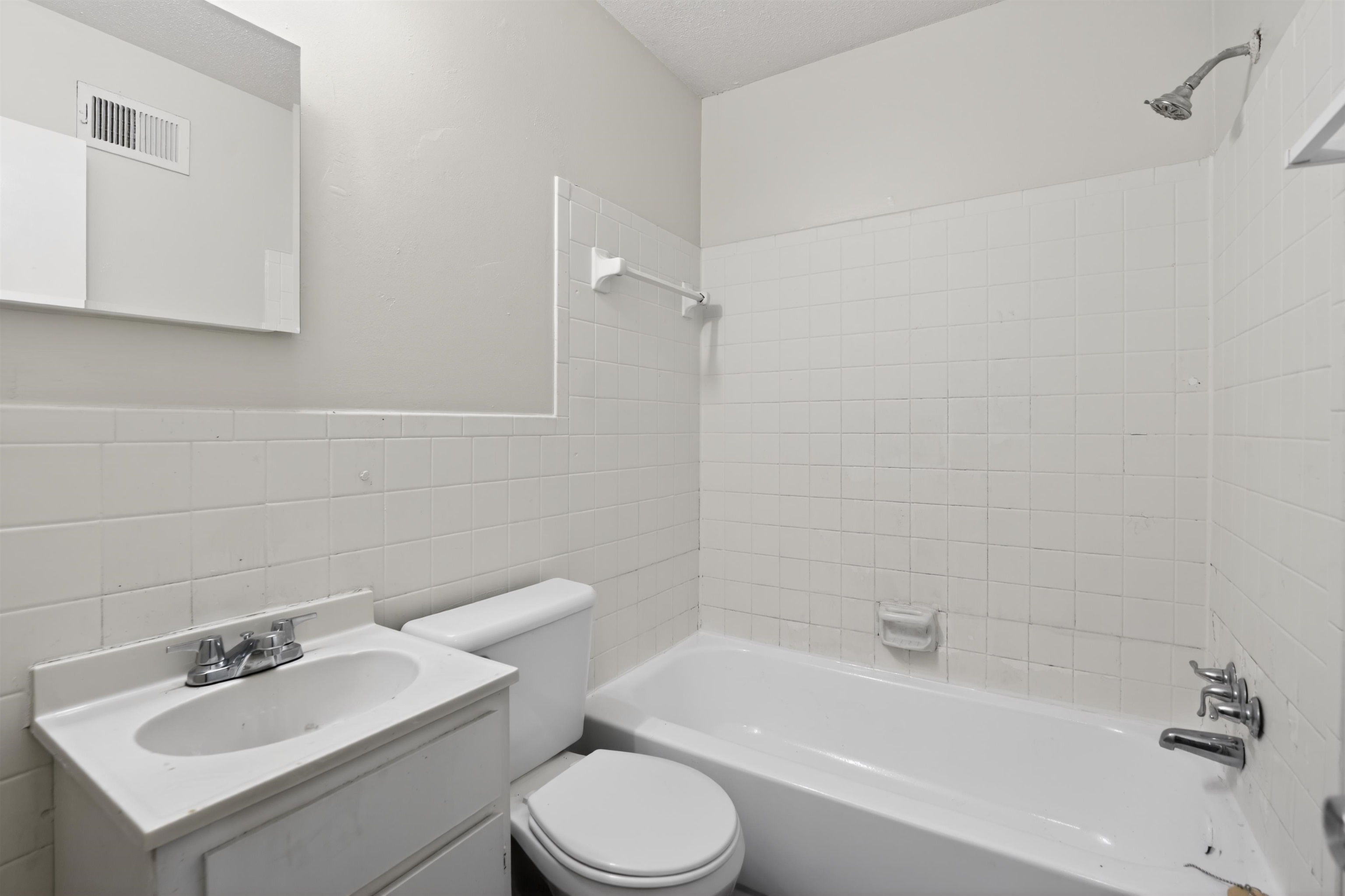 3152 Mackham Avenue Memphis, TN 38118 - Photo 15 of 16 Bathroom featuring a white vanity with integrated sink, chrome faucet, toilet, and a white tiled shower/tub combination with a chrome showerhead