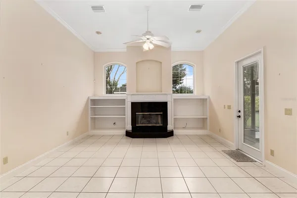 a view of a livingroom with a fireplace a chandelier and windows