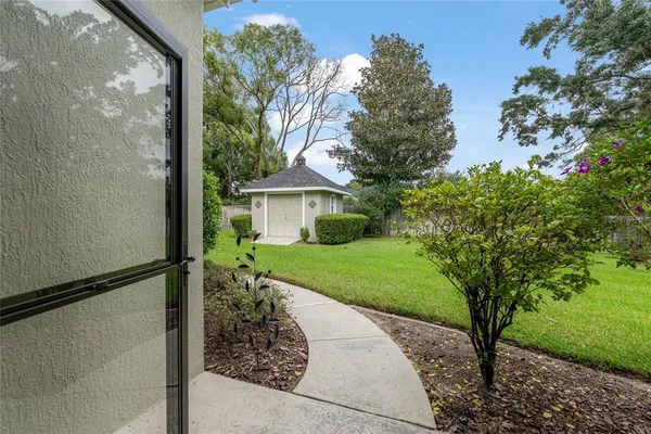 a sign that is sitting in front of a brick house with large trees