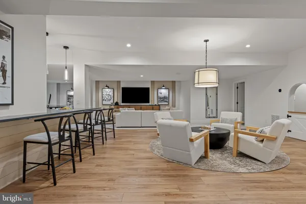 a living room with couches chairs and a dining table with wooden floor