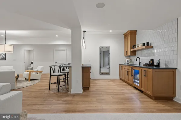 a large white kitchen with stainless steel appliances kitchen island granite countertop a stove a sink a refrigerator and white cabinets with wooden floor