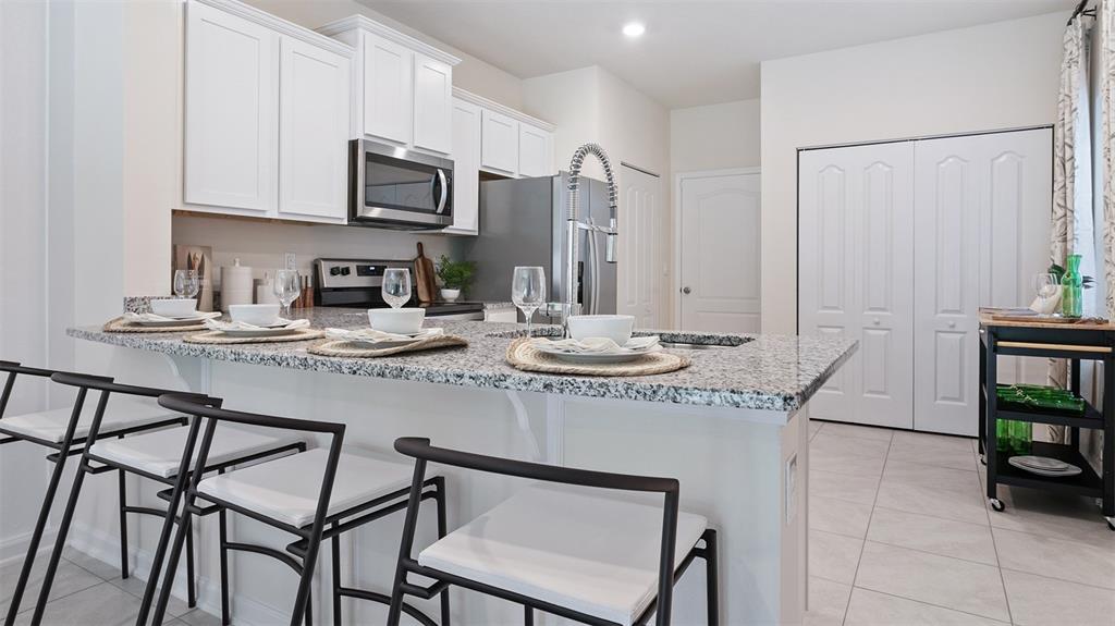 a kitchen with stainless steel appliances kitchen island granite countertop a table chairs in it and white cabinets