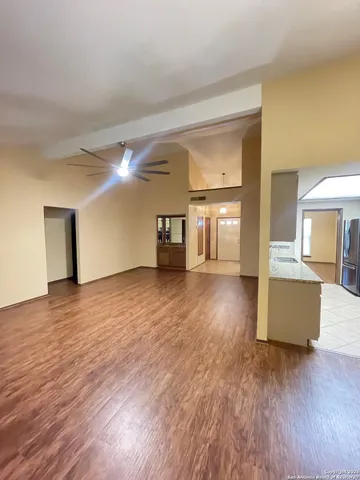 a view of a big room with wooden floor and a kitchen