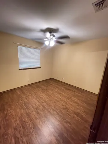 an empty room with a chandelier fan and windows