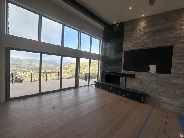 1918 Chimney Rock Road Heber City, UT 84032 - Photo 24 of 74 Expansive wall of windows with transom panels, a multi-panel sliding glass door leading to a balcony, a stone accent wall, a built-in fireplace hearth with a dark stone surface, and wide plank wood-finish flooring