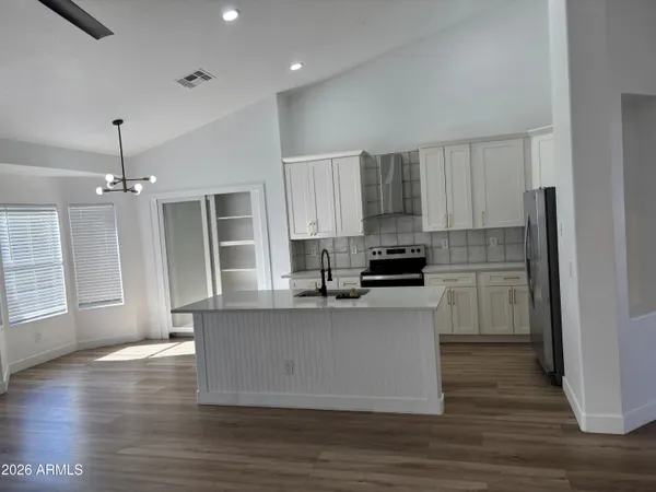 a kitchen with stainless steel appliances granite countertop a refrigerator a stove top oven a sink and dishwasher with wooden floor