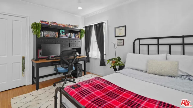 a bedroom with a bed and a flat tv screen on dresser