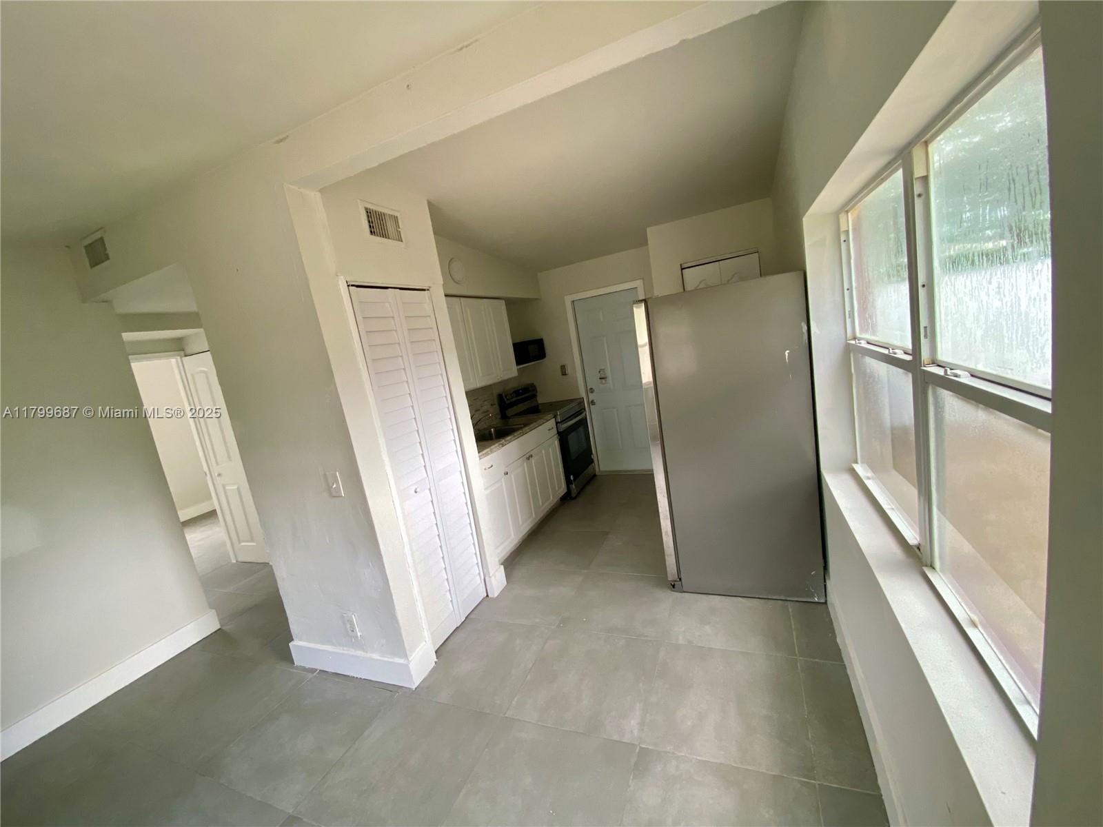 2340 Service Road Opa-Locka, FL 33054 - Photo 8 of 29 a view of a refrigerator in kitchen and an empty room