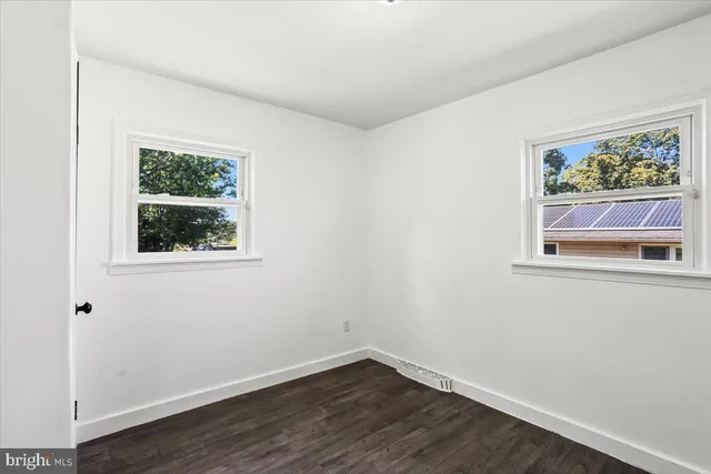 a view of an empty room with wooden floor and window
