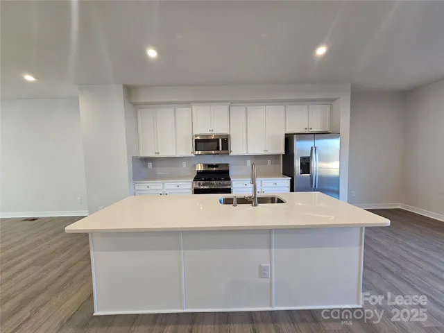 a large white kitchen with kitchen island sink refrigerator and cabinets