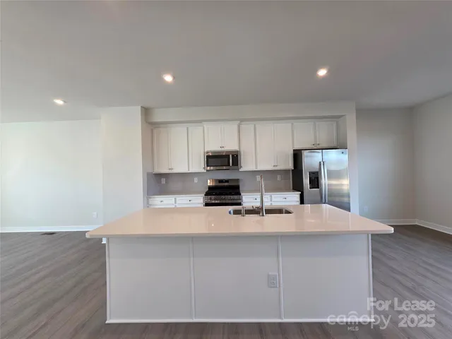 a large kitchen with stainless steel appliances a large counter top and wooden floors