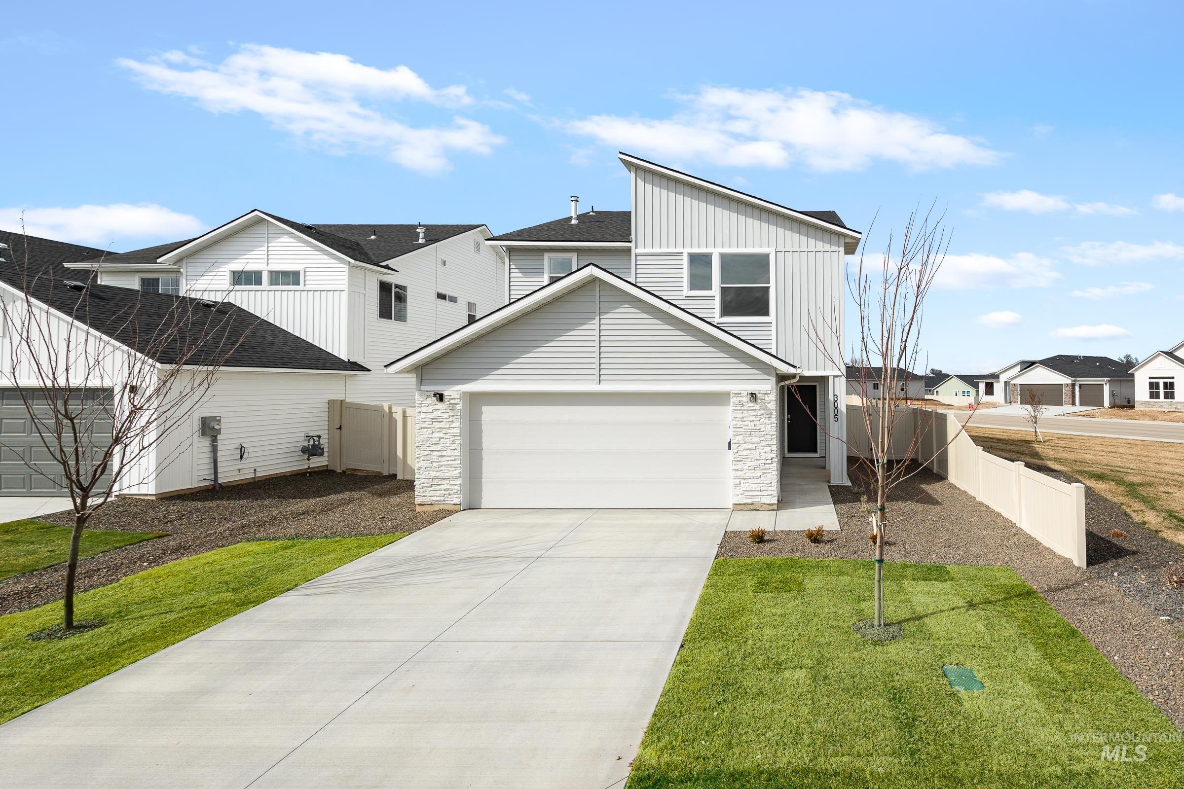 View of front of home with a residential view, board and batten siding, stone siding, driveway, and a garage