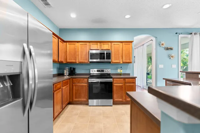 a kitchen with stainless steel appliances granite countertop a sink a stove and a refrigerator