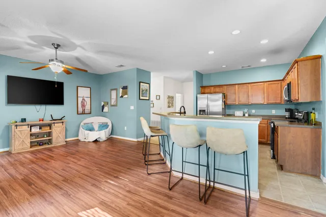 a living room with furniture a flat screen tv and kitchen view